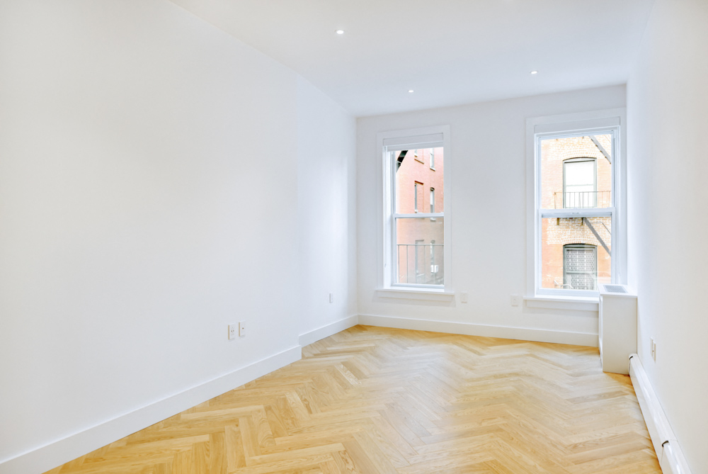 a living room with a wood floor and two windows